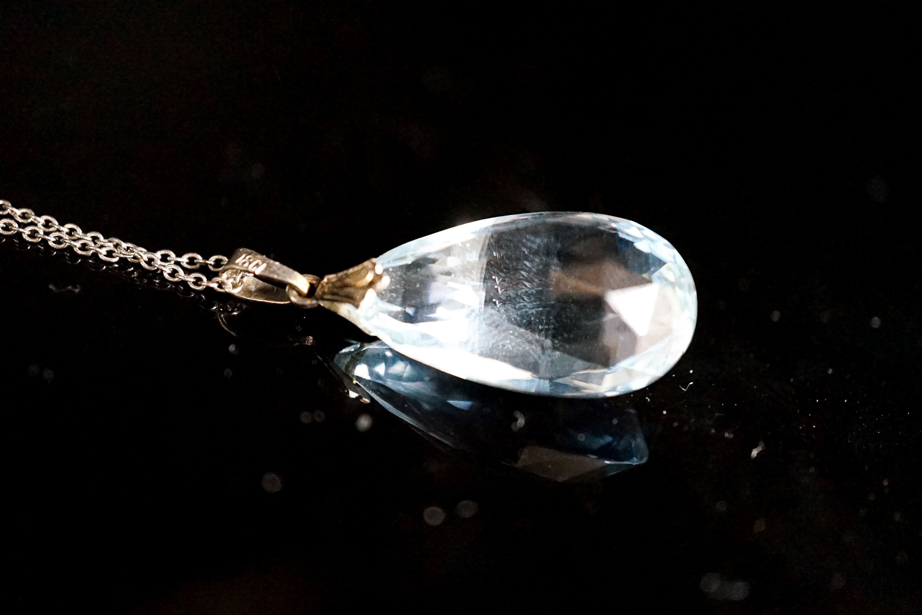 An 18ct mounted facetted pear cut aquamarine set pendant, 33mm, on a 375 white metal fine link chain, 45cm, gross weight 5.2 grams.